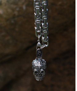 A Maramalive™ Gothic Pendant Necklace hanging from a chain on a rock.