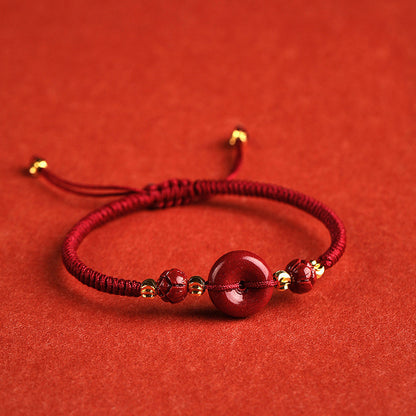 A woman's hand with a Maramalive™ Men's And Women's Fashion Cinnabar Peace Buckle Woven Bracelet on it.