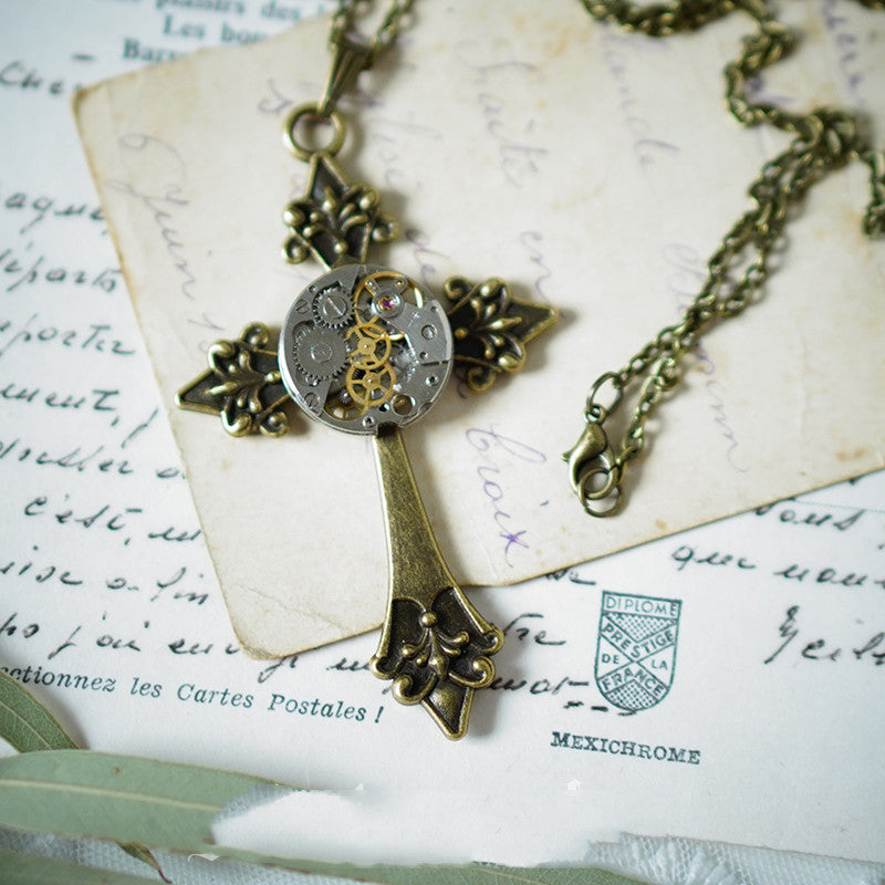 A Vintage Steampunk Gear Cross Pendant Necklace by Maramalive™ in a box on a table.
