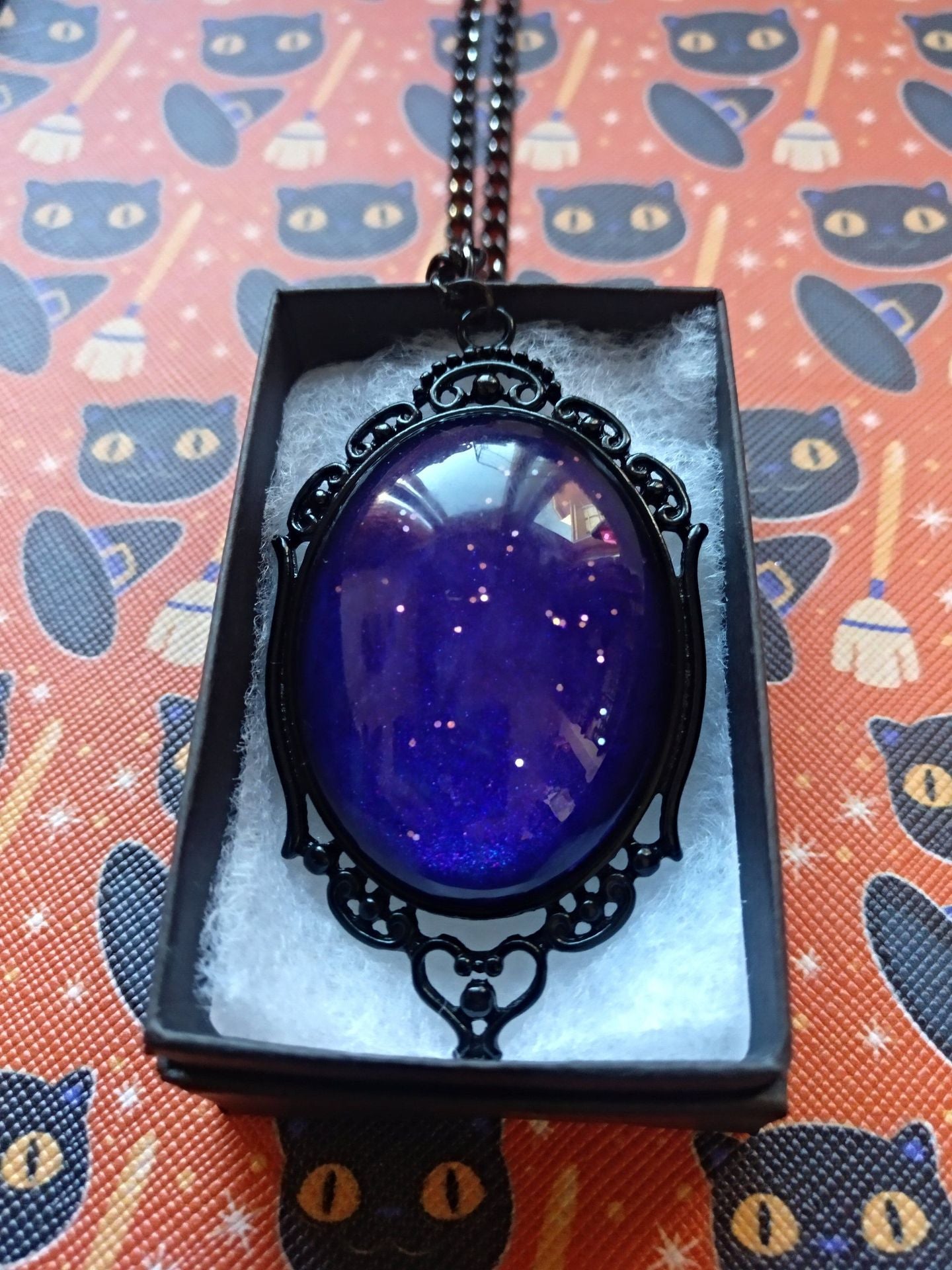 A Maramalive™ Plum Sunset Talisman: Purple Night Sky Gothic Necklace in a box with a cat on it.