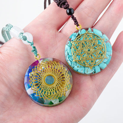 A hand holding two European And American Fashion Men's And Women's Necklace Pendants with a mandala design on them from Maramalive™.
