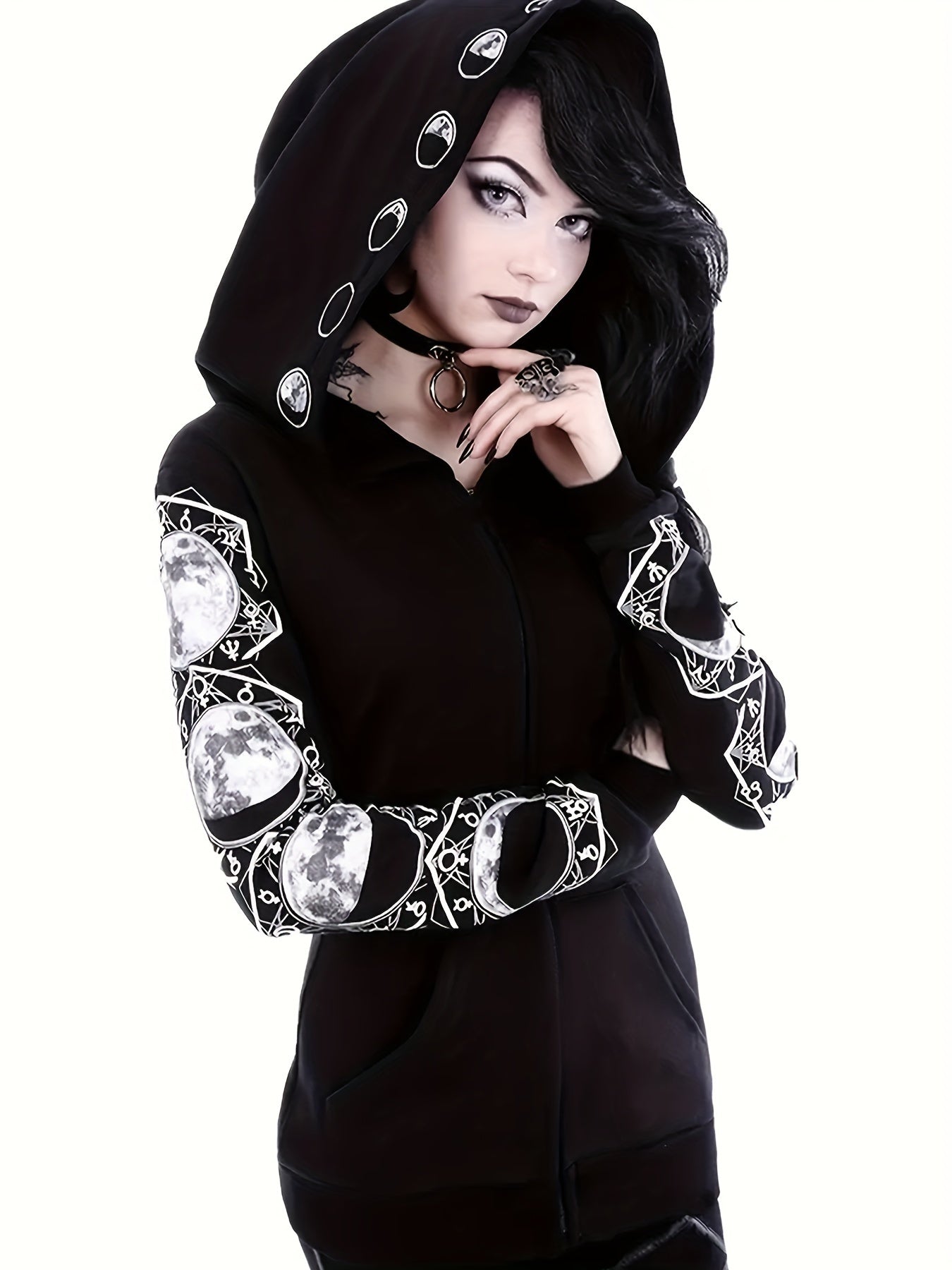 Person wearing a Maramalive™ Plus Size Gothic Sweatshirt, Women's Plus Moon Print Long Sleeve Zipper Slight Stretch Hoodie With Pockets with dark hair and makeup, standing casually against a white background.