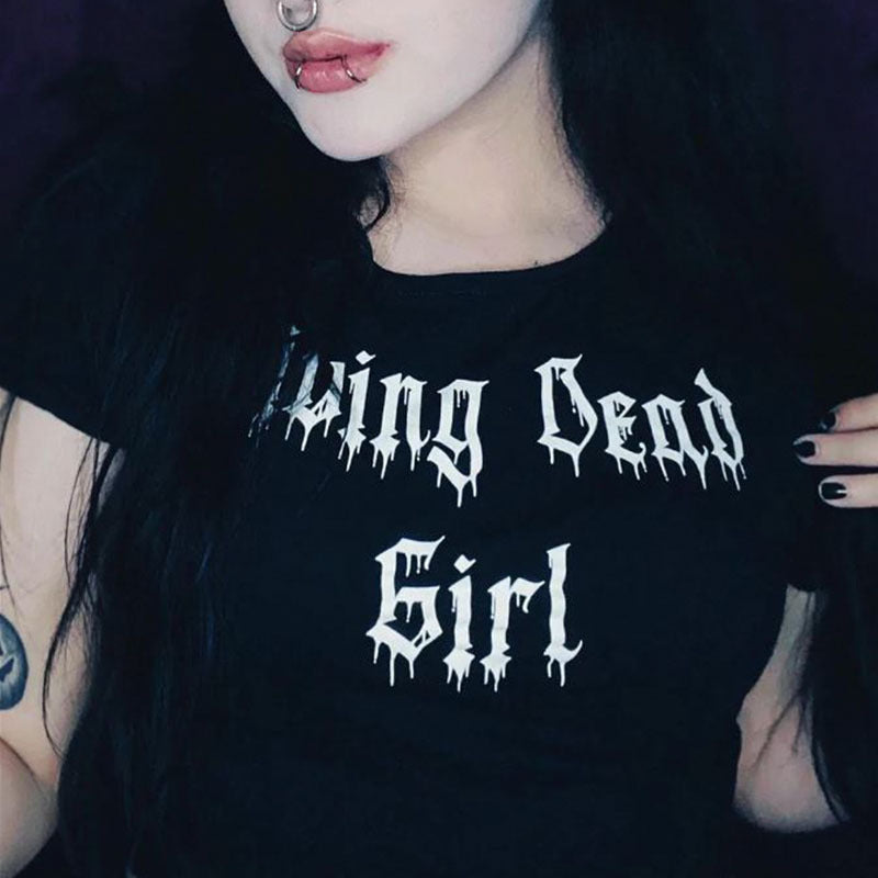 A person with dark hair and a nose ring is wearing a black Maramalive™ Gothic Style Printed Top Short Sleeve that reads "Living Dead Girl" in white dripping letters.