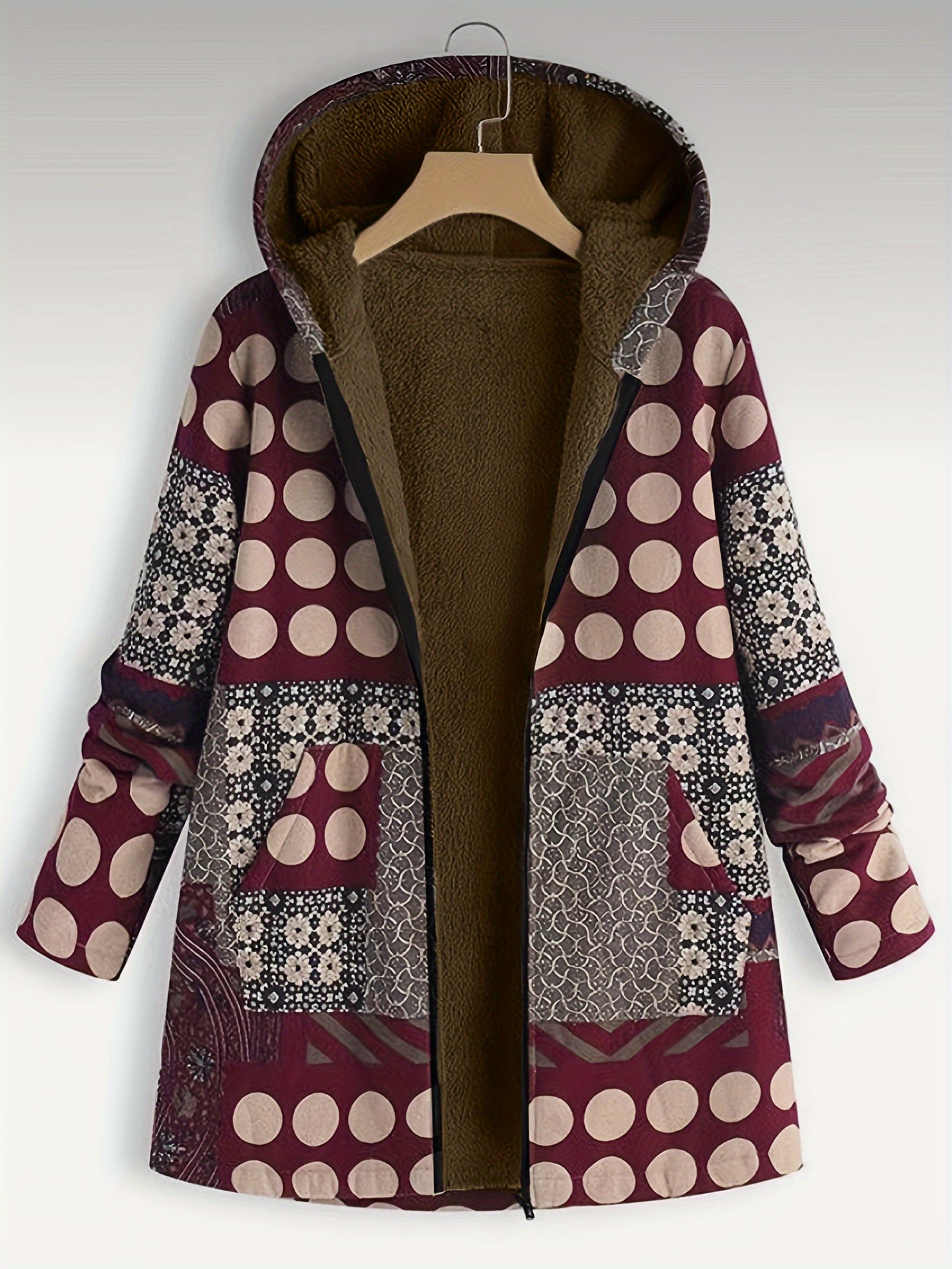 A Plus Size Boho Coat, Women's Plus Patchwork Print Liner Fleece Long Sleeve Zipper Hooded Tunic Coat With Pockets by Maramalive™ hangs on a wooden hanger. The coat, perfect for winter, features various patterns including polka dots and has an inner brown fleece lining, crafted from polyester for extra warmth.