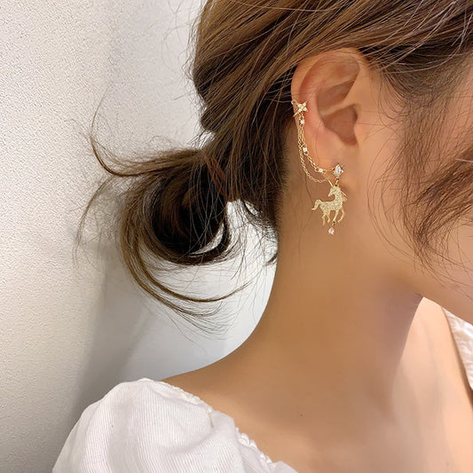 A close up of a person wearing a pair of Maramalive™ Unicorn themed stud earrings which includes a chain to a cuff for your wife, daughter, any Unicorn fan with this Personality Jewelry.