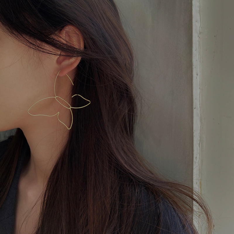 A woman wearing a pair of Maramalive™ Butterfly Hollow Earrings.