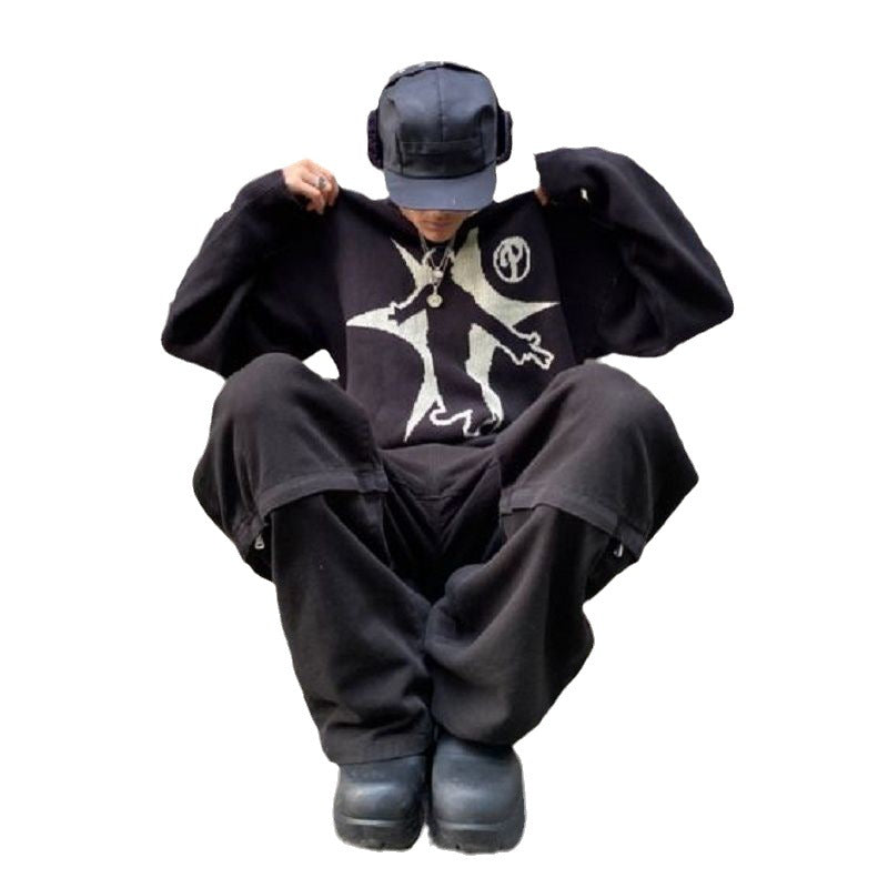 Person in black attire, including a Maramalive™ Hip-Hop Street Gothic Print Knitted Sweater with a star design and geometric pattern, baggy pants, boots, and a cap with headphones, sitting on the ground with knees pulled up. A perfect depiction of street fashion meeting Gothic style.