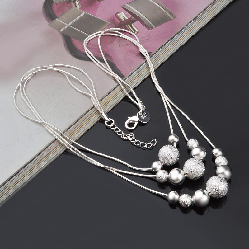 A Maramalive™ silver necklace with silver beads on top of a book.
