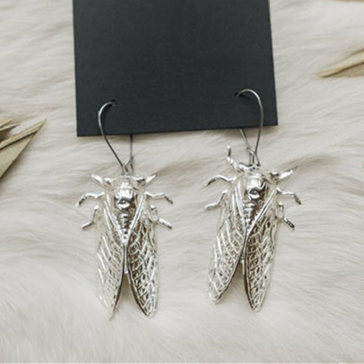 A person holding a pair of Maramalive™ Gothic Cicada Earrings.