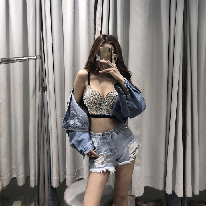 A woman is taking a selfie in a fitting room, wearing the Maramalive™ Gypsophila shining studded waistcoat strapless tube top strap that flaunts various bra sizes, a blue denim jacket, and distressed denim shorts.