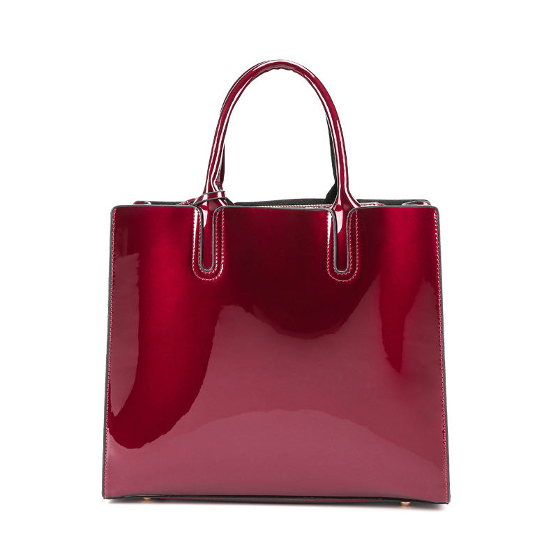 A burgundy Patent leather handbag with two purses, a wallet, and a zipper pocket for convenience.