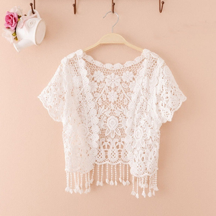 A loose type Maramalive™ white lace cardigan hanging on a pink wall.