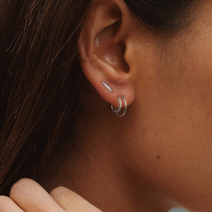 A woman's ear with a Maramalive™ S925 Sterling Silver Single Row Ball Stud Earrings White Gold Color.