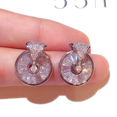 A pair of Maramalive™ diamond stud earrings pendant for women in a box next to a shell.