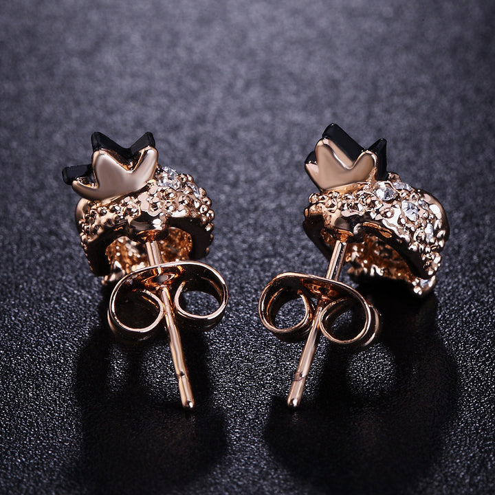 A pair of Maramalive™ gold-plated skull earrings with black diamonds.