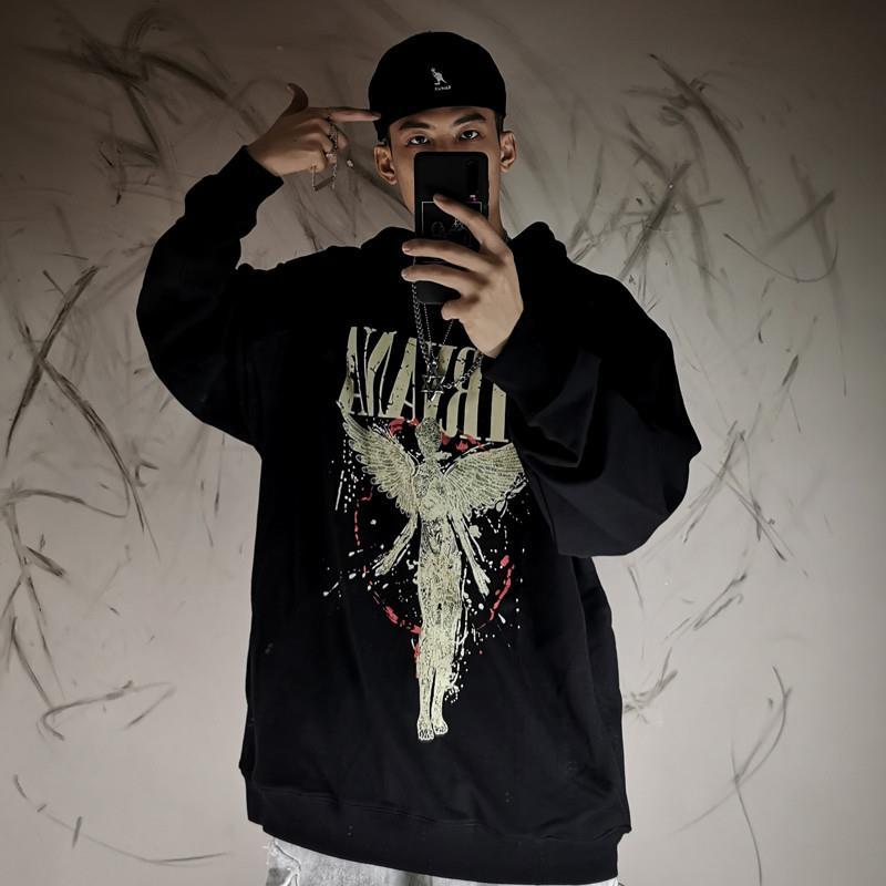 A person wearing a black Oversized Punk Style & Hoodie Sweatshirt: Edgy Look by Maramalive™ with a graphic design takes a mirror selfie using a smartphone. The background shows abstract wall art.