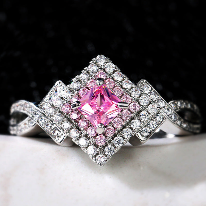 A Maramalive™ pink sapphire and diamond ring on a black background.