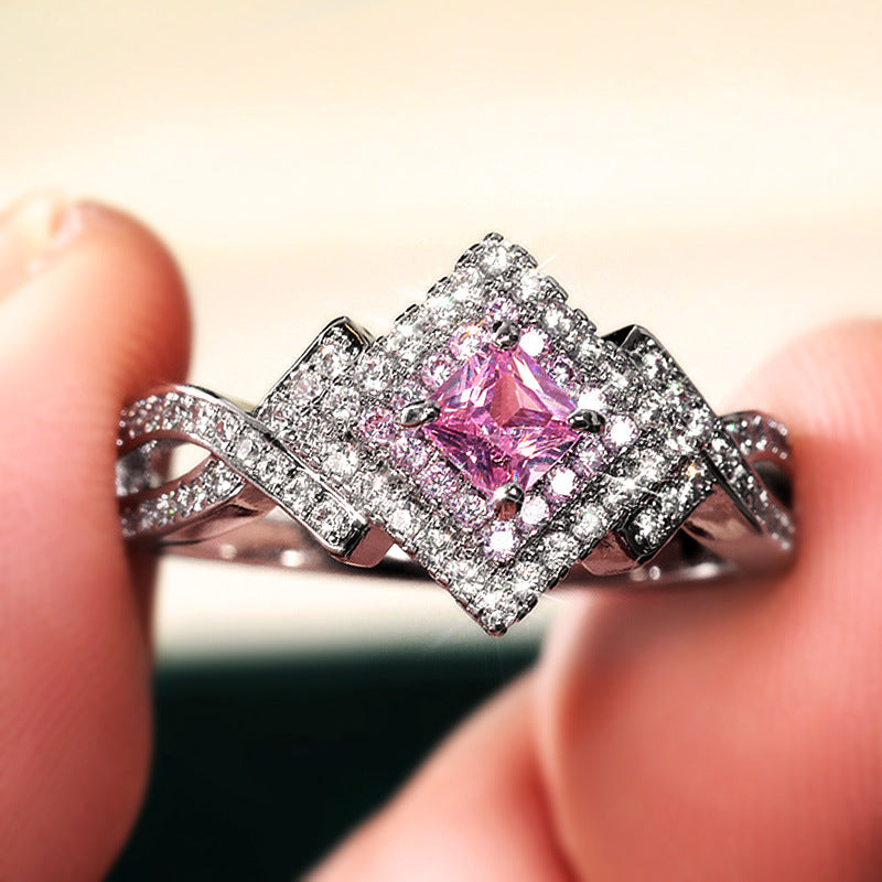 A Maramalive™ pink sapphire and diamond ring on a black background.