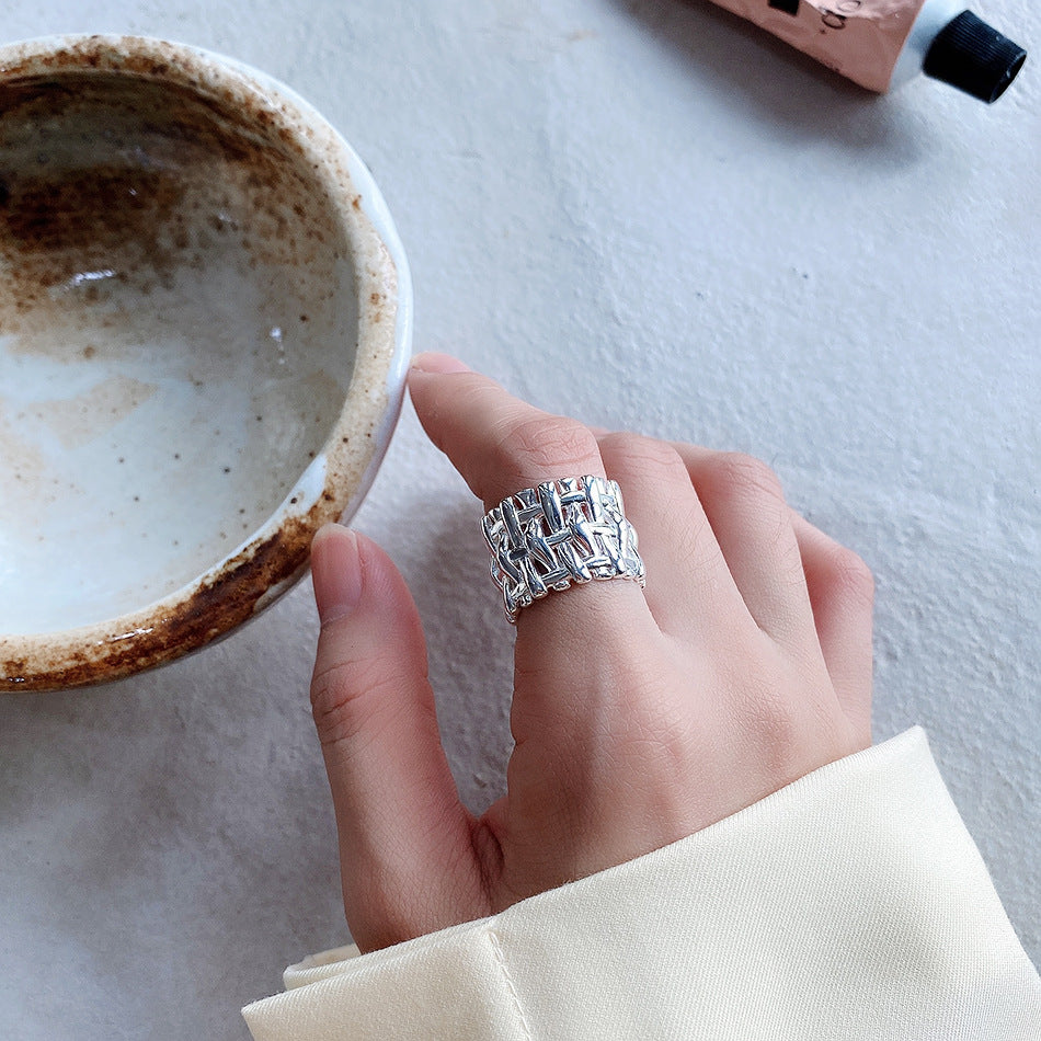 A hand holding a Maramalive™ Understated skillfully made Woven Ring Women Cross Wide Simple Ring and a cup of coffee.