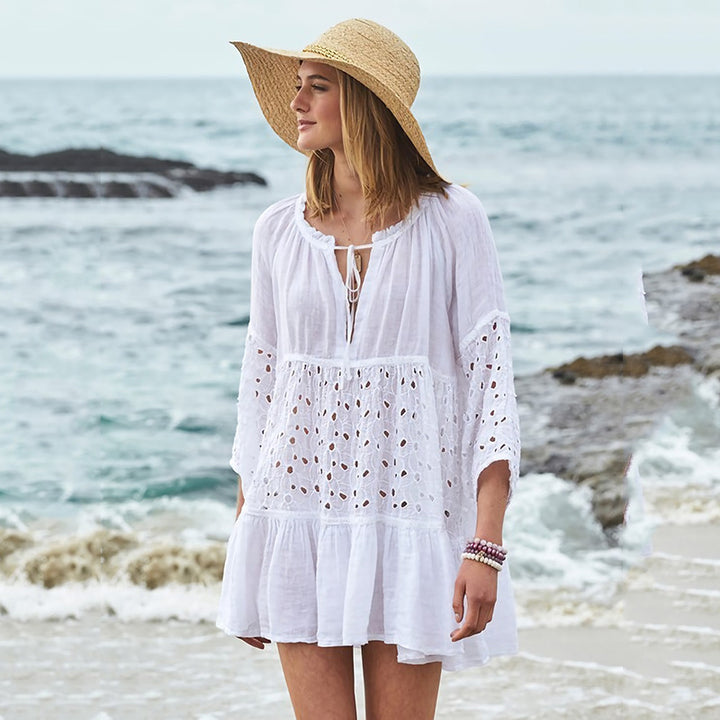 A woman in a sleeveless white Sun Protection Clothing Women Loose Bikini Blouse and hat standing on a beach. Brand Name: Maramalive™