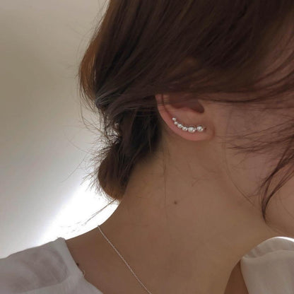 A woman wearing a white shirt and Maramalive™ Sterling Silver Ball Earrings ear cuffs.