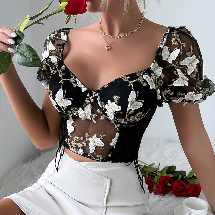A person in a Maramalive™ Ladies New Hot Girl Backless See-through Camisole and white skirt, embodying European and American style, holds a red rose. Additional red roses lie on a white surface beside them.