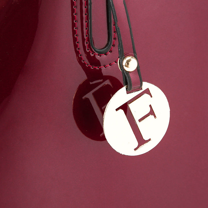 A burgundy Patent leather handbag with two purses, a wallet, and a zipper pocket for convenience.