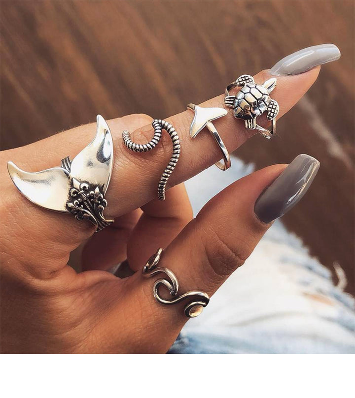 A woman's hand holding a Maramalive™ Geometric Turtle Mermaid Ring set.