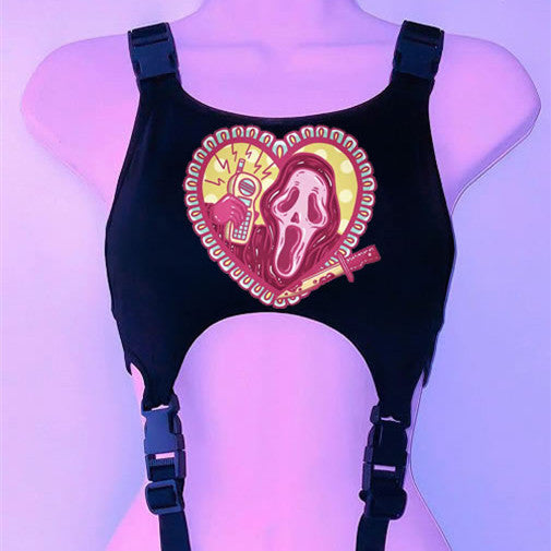 A '90s Throwback Y2K Gothic Style Cropped Vest for Goths in black faux leather material with two buckles, featuring a graphic of a stylized screaming face, microphone, and ornate heart design on the front. The image is set against a purple background, embodying vintage-inspired goth style by Maramalive™.