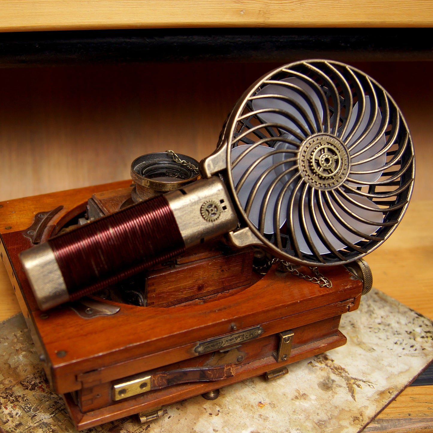 A Maramalive™ Steampunk Retro Portable Handheld Folding USB Charging Mini Fan sitting on top of a wooden box.