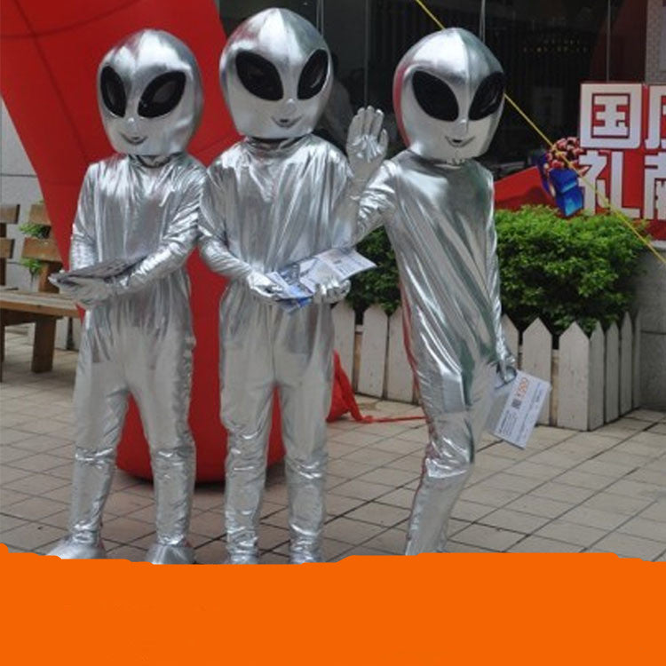 Three individuals dressed in Maramalive™ Alien show costume Suits stand outdoors on a paved area, holding pamphlets and one waving at the camera, looking like they're ready for a sci-fi convention.