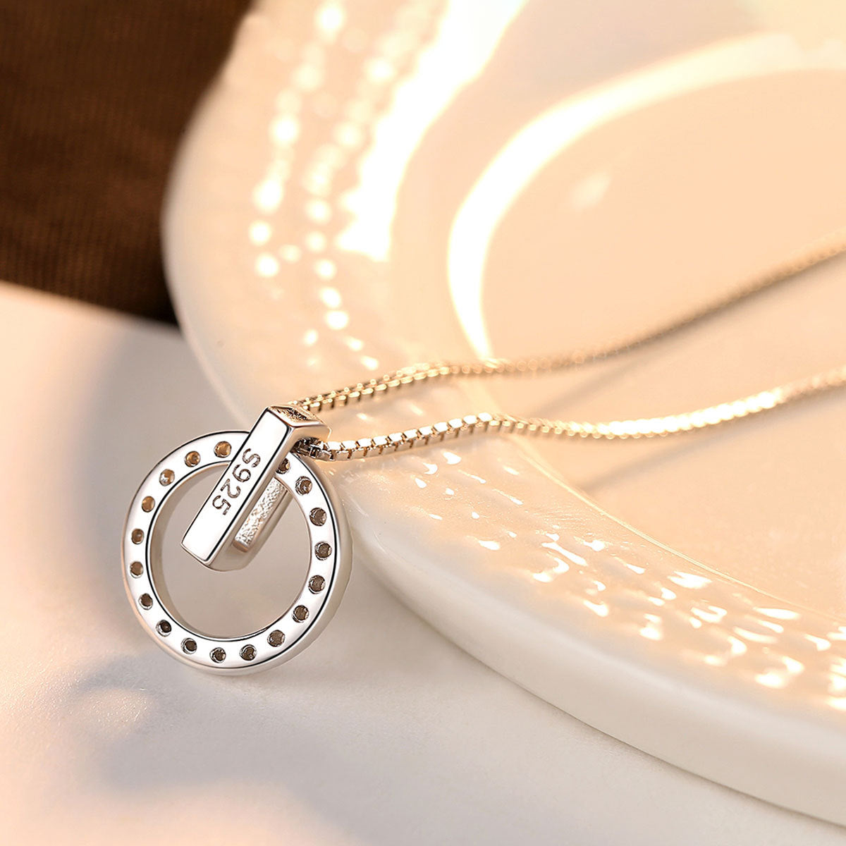 A Maramalive™ Round Pendant Necklace with a circle pendant on top of a plate.
