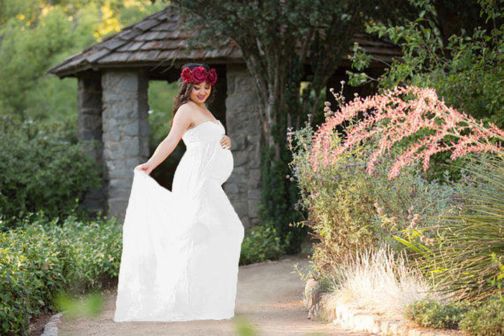 A pregnant woman in a red Maramalive™ chiffon mop skirt dress posing in a garden.
