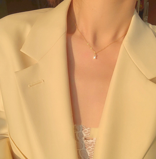 A woman in a yellow jacket wearing a Maramalive™ Extremely Sparkling Elegant Small Square Diamond Women's Clavicle Chain.