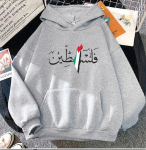 A Maramalive™ Autumn And Winter Fleece Warm Hoodie Jacket Casual Sweatshirt in gray with stunning Arabic calligraphy reading "Palestine" and a design featuring the colors of the Palestinian flag. This cozy winter hooded pullover is displayed on a surface with books and a pair of white shoes nearby.