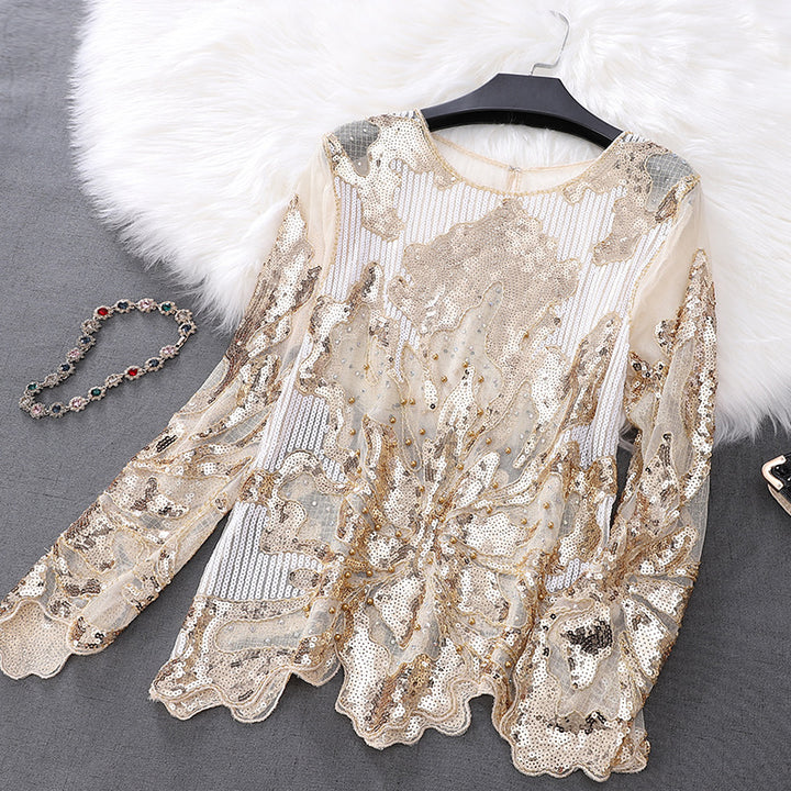 A **Maramalive™ Petal Long Sleeve Beaded Sequins Slimming Lace Versatile Mesh Plus Size Top**, adorned with gold sequins and floral embroidery, featuring petal sleeves for an elegant style, is laid out on a grey surface, with a beaded necklace and a faux fur accent nearby.