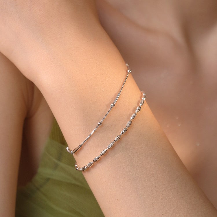 A woman's wrist with two "Geometric Cut Rice Ball Bracelets - Minimalist 925 Sterling Silver Jewelry" by Maramalive™ on it.