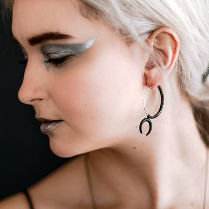 A high-quality European And American Gothic Moon Hoop Punk Exaggerated Black Horns Pagan Earrings woman with silver makeup and hoop earrings.