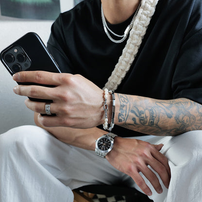 A man sitting on a chair holding a Maramalive™ Square Pearl Bracelets For Men And Women Double Stackers.