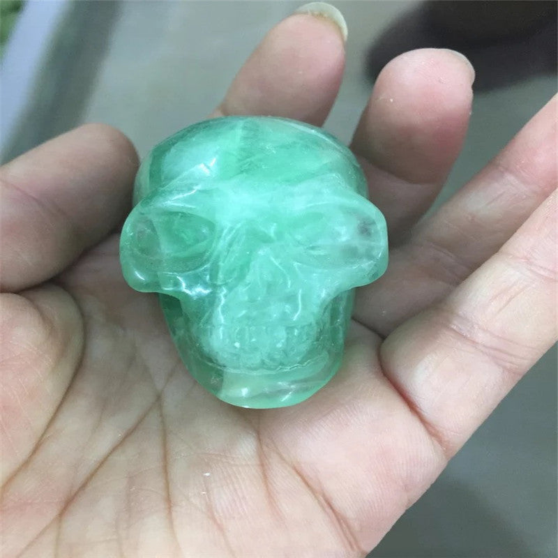 A hand holding a black Maramalive™ Natural crystal skull.