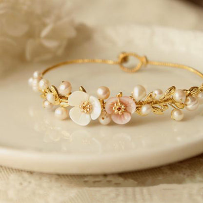 A Natural Shell Carved Pearl Handmade Bracelet Dainty and Minimalistic by Maramalive™ with pearls and flowers on a plate.