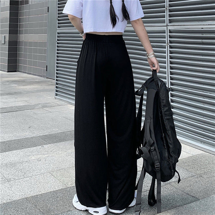A woman making a bold statement in Unique Baggy Trousers with Cut-outs and Fun Style! by Maramalive™ and a white t-shirt and black pants with a unique patterned Harlem vibe.