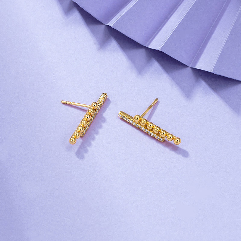 A pair of Maramalive™ Gold-Plated Minimalist Earrings on a purple background.