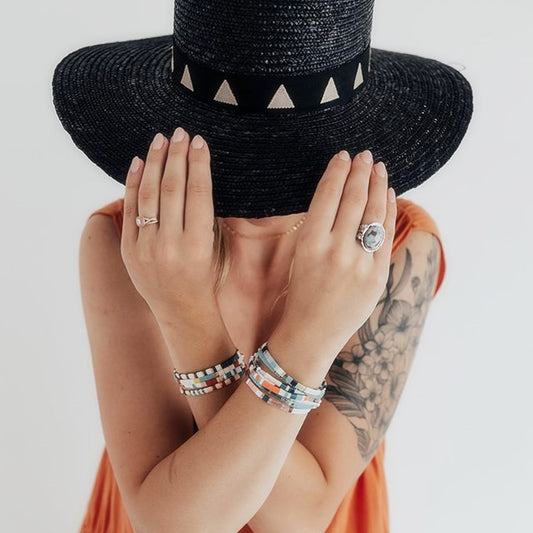 A Maramalive™ handmade woman wearing a hat and bracelets adorned with Bohemian Style Creative Handmade Beaded Bracelet beads.