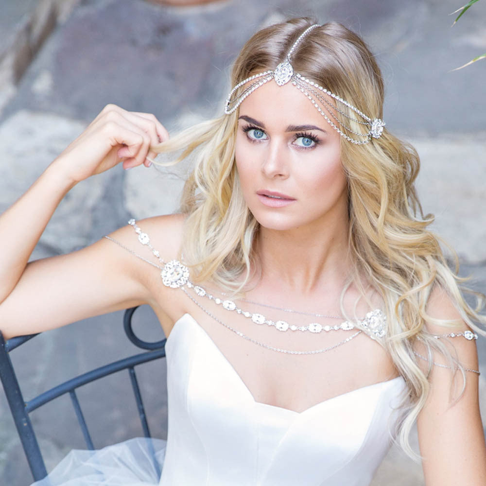 A beautiful bride in a white dress sitting on a chair wearing the Gothic Bridal Tiara by Maramalive™.