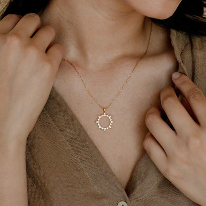 A woman wearing a Minimalist Zircon Sun Necklace by Maramalive™.
