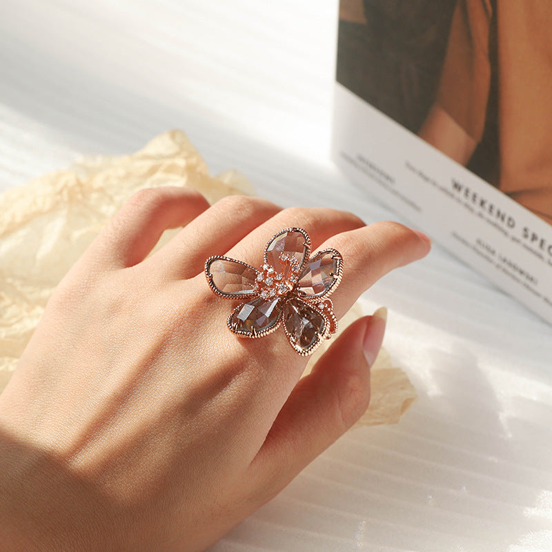 A hand holding a Floral Crystal Ring with a flower on it by Maramalive™.