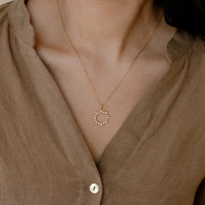 A woman wearing a Minimalist Zircon Sun Necklace by Maramalive™.
