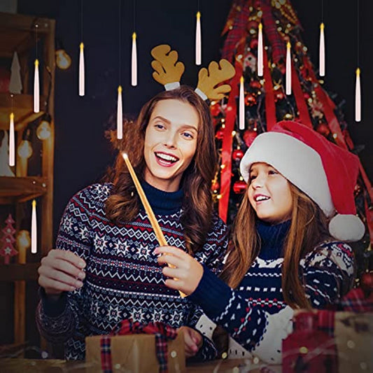 Two girls in santa hats standing in front of a Maramalive™ Flameless Candles With Magic Wand Remote Flickering Warm Light Floating Candles For Home Decor christmas tree.