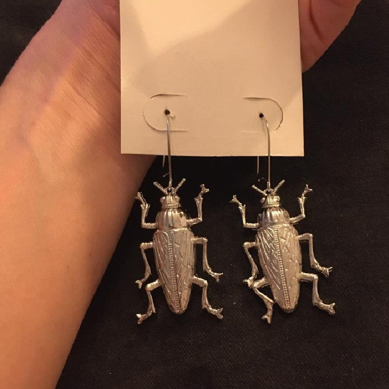 A pair of Gothic Alloy Cockroach Insect Earrings Europe And America by Maramalive™ in a person's hand.